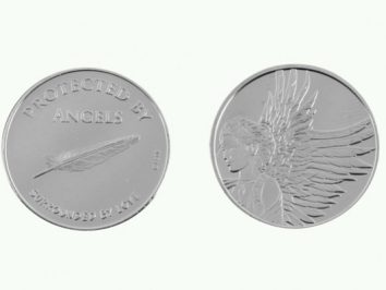 Dwie srebrne monety; jedna z piórem i napisem, druga z wizerunkiem anioła z dużymi skrzydłami.