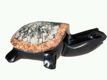 Figurka żółwia wykonana z kamienia, widok z boku na jasnym tle.