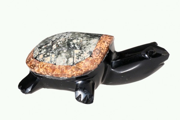 Figurka żółwia wykonana z kamienia, widok z boku na jasnym tle.