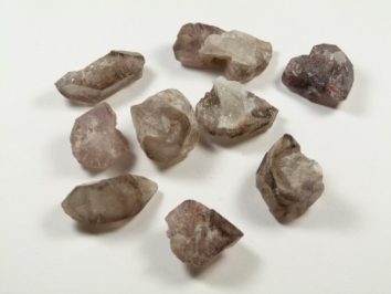 Lepidokrocyt - kamień naturalny, surowy, nieszlifowany. Dziewięć surowych kryształów leży na białym tle.