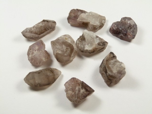 Lepidokrocyt - kamień naturalny, surowy, nieszlifowany. Dziewięć surowych kryształów leży na białym tle.