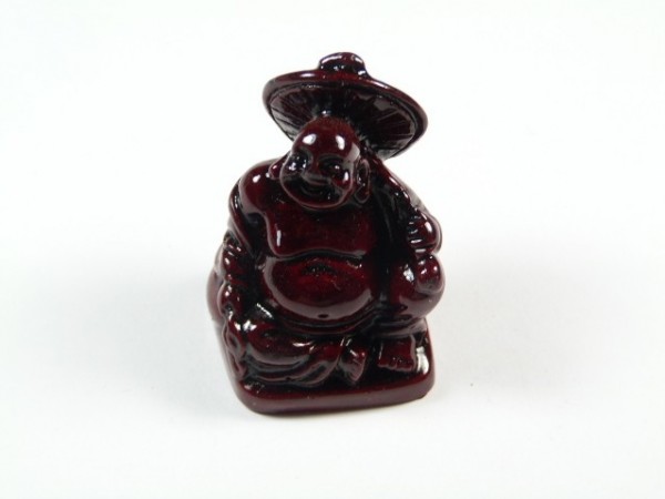 Ciemnoczerwona figurka siedzącego Buddy z kapeluszem, trzymającego kij.