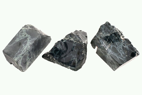 Trzy kawałki ciemnego marmuru z jasnymi żyłkami na jasnym tle.
