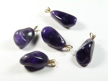 Pięć fioletowych zawieszek z kamieniami ametystu na białym tle.
