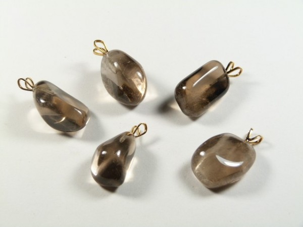 Pięć brązowych kamieni z zawieszkami leży na białym tle.