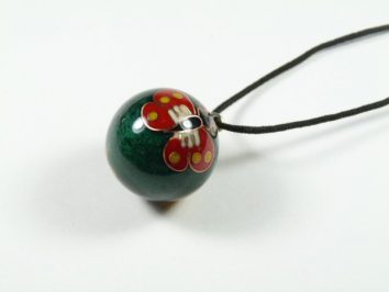 Zielona kulka na sznurku z namalowanym czerwonym motylem.