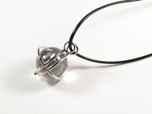 Srebrny wisior z kulistym wisiorkiem na czarnym rzemyku, na białym tle.