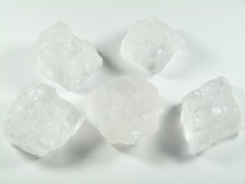 Pięć dużych kryształów soli na białym tle.