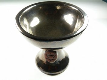 Czarna ceramiczna misa na nóżce z symbolem geometrycznym na podstawie.