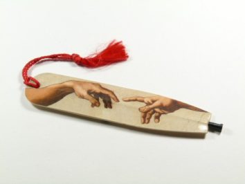 Zakładka do książki z czerwonym sznurkiem i grafiką dwóch zbliżających się dłoni.