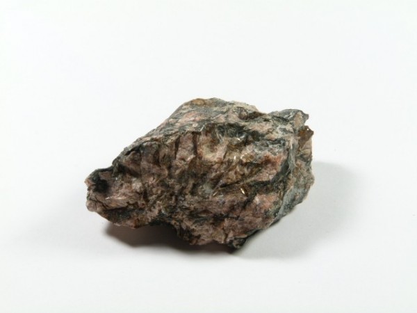 Nieregularny kawałek surowej skały na białym tle.