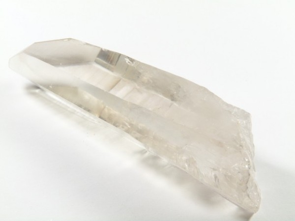 Przezroczysty kryształ kwarcu leży na białym tle.