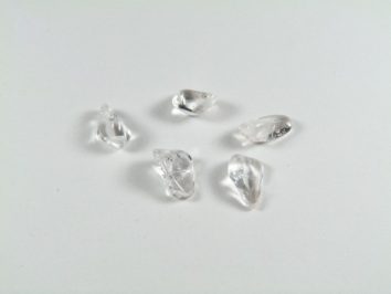 Pięć przezroczystych kryształków leży na białym tle.