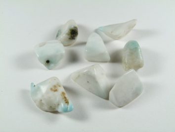 Siedem polerowanych, jasnych kamieni larimaru na białym tle.