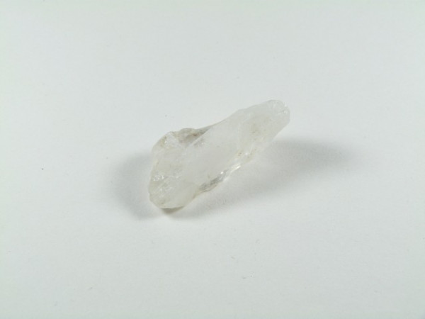 Przezroczysty kryształ kwarcu leży na białym tle.