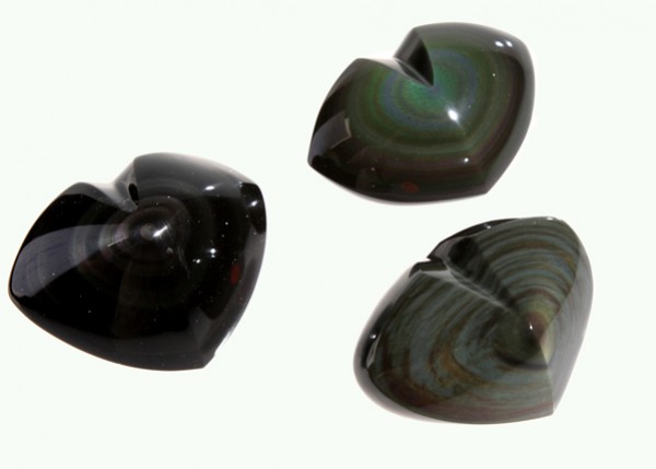 Trzy błyszczące kamienie obsydianu w kształcie serca na jasnym tle.