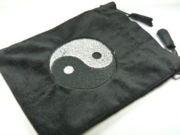 Czarny woreczek z symbolem yin-yang na środku, leżący na białym tle.