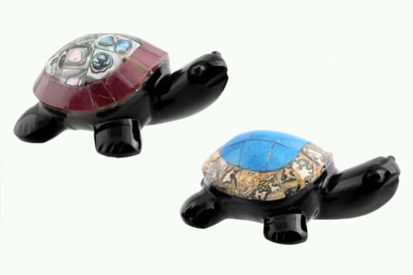 Dwie figurki żółwi z kolorowymi muszlami na pancerzach na białym tle.
