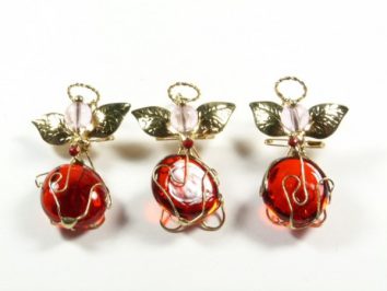 Trzy ozdobne aniołki z czerwonych kulek, drutu i złotych skrzydeł, ustawione w rzędzie.