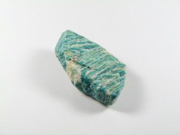 Niebiesko-zielony, surowy minerał amazonit na białym tle.