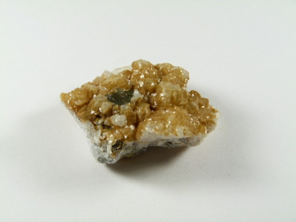 Syderyt - kamień naturalny, surowy, nieszlifowany. Kawałek błyszczącego, żółtobrązowego minerału na białym tle.