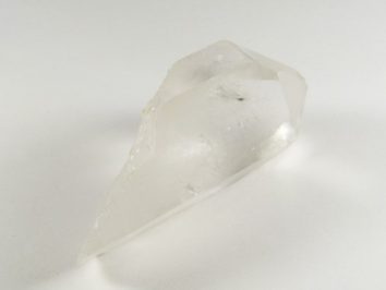 Przezroczysty kryształ kwarcu leżący na białym tle.