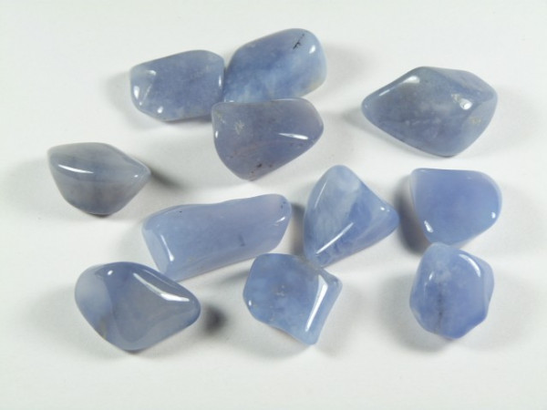 Na białym tle leży kilka niebieskich, wypolerowanych kamieni szlachetnych.