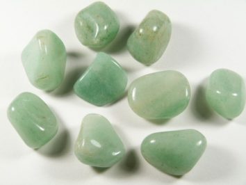 Dziewięć zielonych, oszlifowanych kamieni leży na białym tle.
