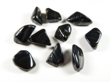 Dziewięć czarnych, polerowanych kamieni agatowych leży na białym tle.