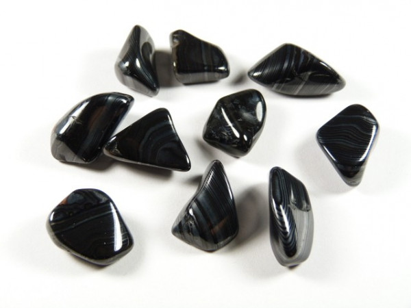 Dziewięć czarnych, polerowanych kamieni agatowych leży na białym tle.