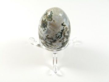 Jajko agat mszysty z podstawką. Jajko z kamienia z zielonymi wzorami, ustawione na przezroczystej podstawce.