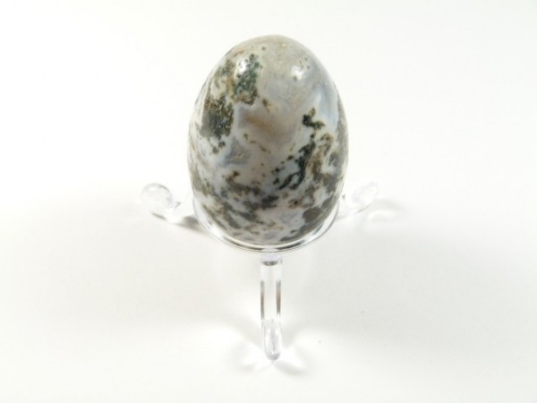 Jajko agat mszysty z podstawką. Jajko z kamienia z zielonymi wzorami, ustawione na przezroczystej podstawce.