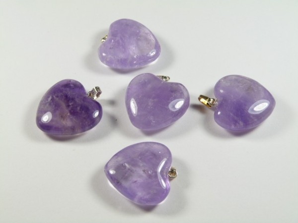 Ametyst serce/ serduszko wisiorek. Pięć fioletowych wisiorków z kamieni w kształcie serca leży na białym tle.