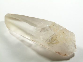 Przezroczysty kryształ kwarcu leżący na białym tle.