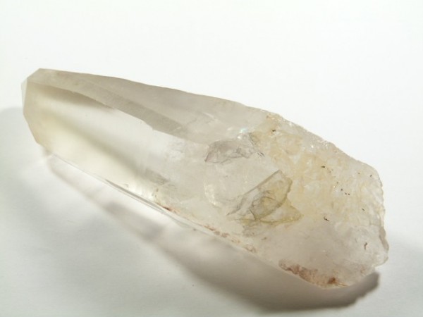 Przezroczysty kryształ kwarcu leżący na białym tle.