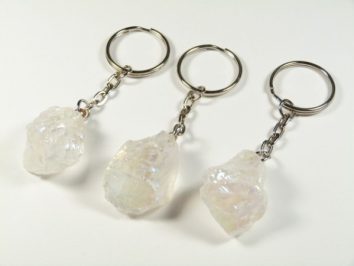 Trzy breloki z przezroczystymi, surowymi kryształami na metalowych łańcuszkach.