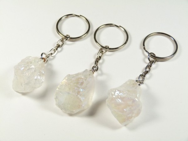 Trzy breloki z przezroczystymi, surowymi kryształami na metalowych łańcuszkach.
