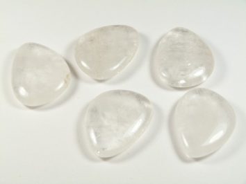 Kryształ górski szlifowany - płaski kamień. Pięć gładkich, przezroczystych kamieni leży na białym tle obok siebie.