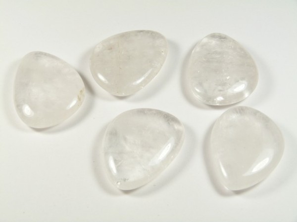 Kryształ górski szlifowany - płaski kamień. Pięć gładkich, przezroczystych kamieni leży na białym tle obok siebie.