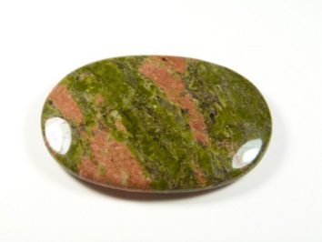 Unakit - kamień gładzony, polerowany, szlifowany. Polerowany, owalny kamień o zielono-różowych pasach na białym tle.