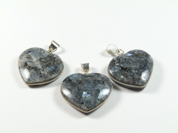 Trzy serca z kamienia labradoryt, oprawione w srebro, leżące na białym tle.