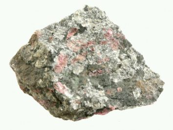 Eudialit - kamień naturalny, surowy, nieszlifowany. Szara skała z różowymi minerałami na jasnym tle.
