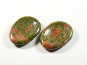 Unakit szlifowany - płaski kamień. Dwa owalne, polerowane kamienie w kolorach zielonym i czerwonym na białym tle.