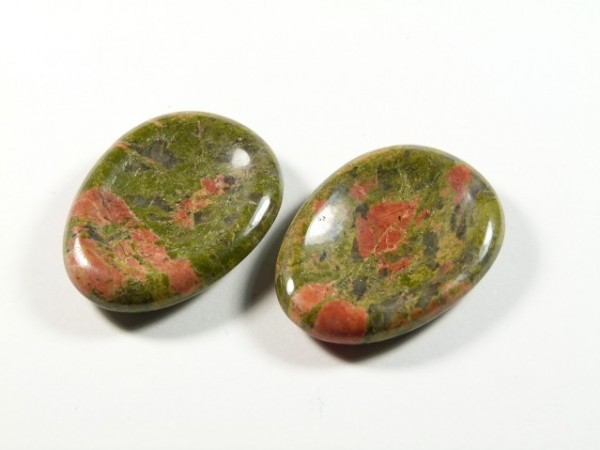 Unakit szlifowany - płaski kamień. Dwa owalne, polerowane kamienie w kolorach zielonym i czerwonym na białym tle.