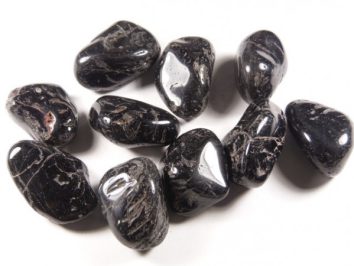 Kilka czarnych, wypolerowanych kamieni leży na białym tle.