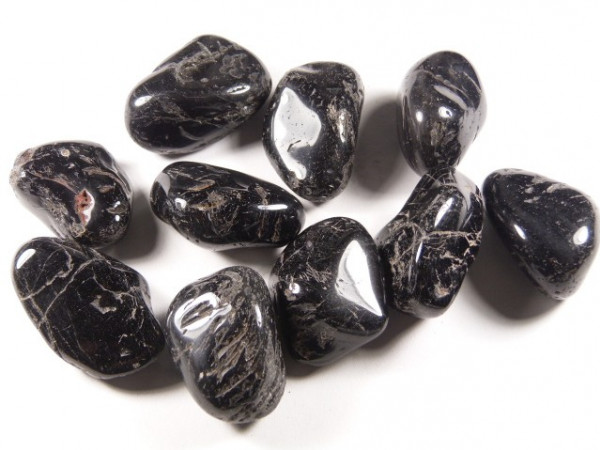 Kilka czarnych, wypolerowanych kamieni leży na białym tle.
