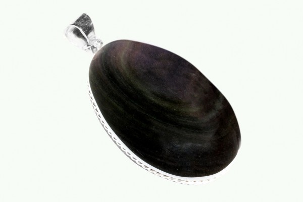Owalny wisior z ciemnym kamieniem oprawionym w srebro, na jasnym tle.