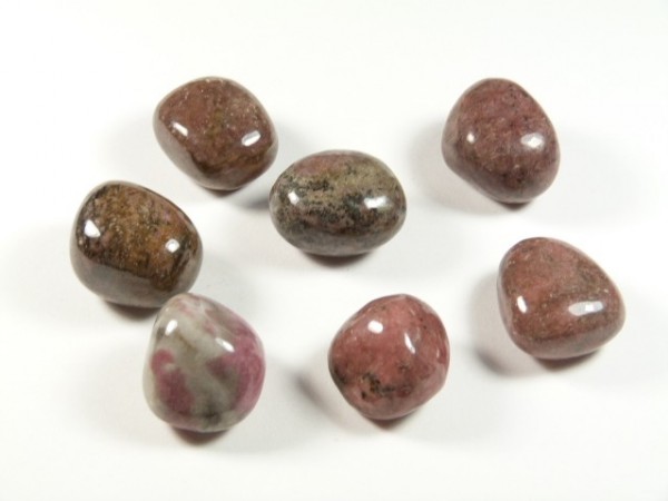 Siedem wygładzonych kamieni o różnych odcieniach brązu i różu na białym tle.