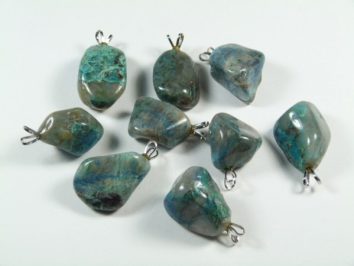 Osiem zielono-niebieskich kamieni z zawieszkami do naszyjników na białym tle.
