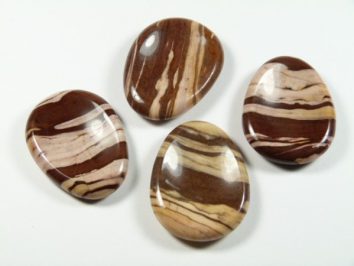 Cztery gładkie, polerowane kamienie w brązowe i kremowe pasy na białym tle.